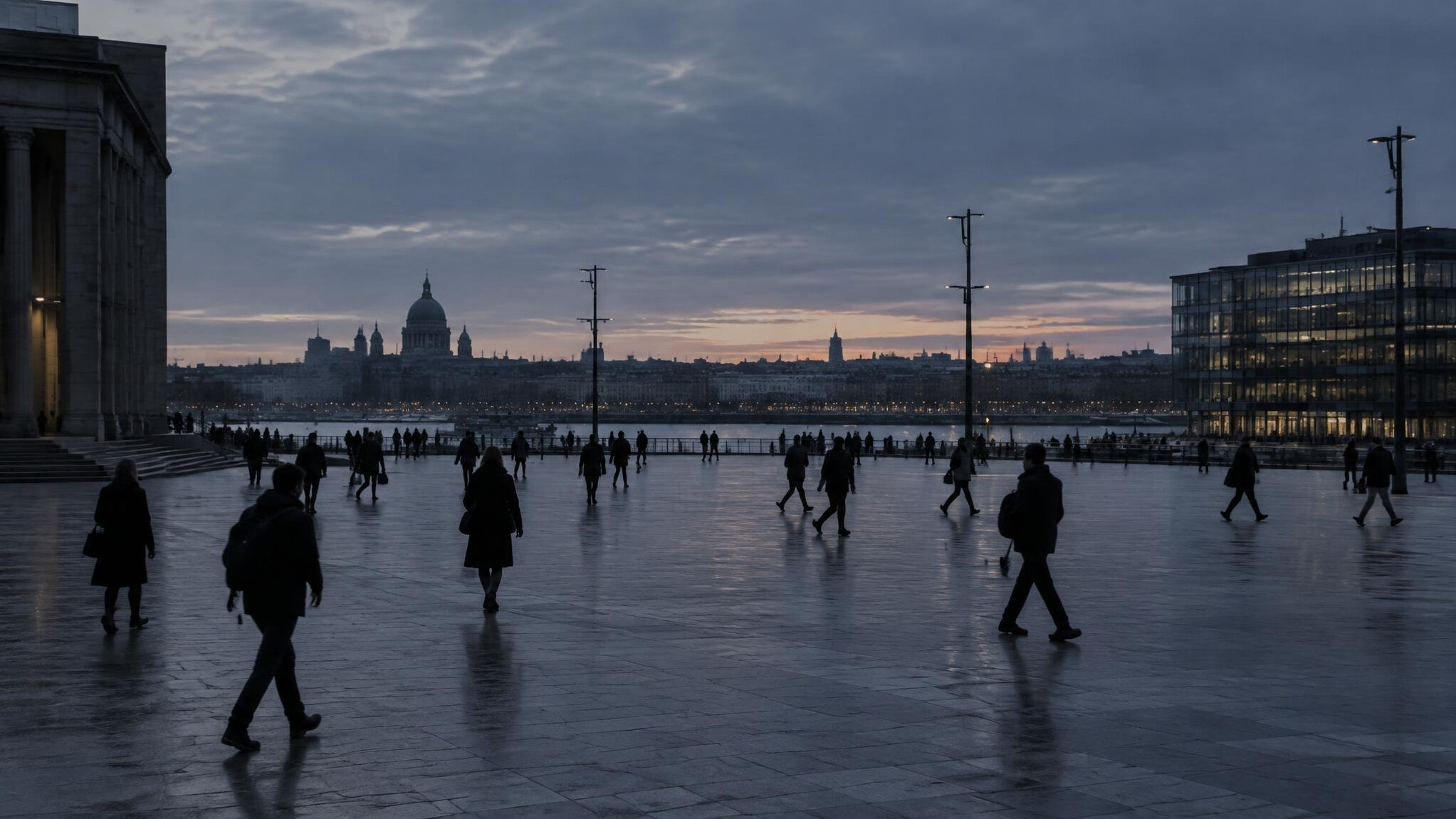 Distant anonymous silhouettes of people crossing a plaza at dusk